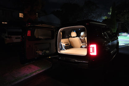 Night-time exterior view of a Denza B8 with the tailgate open and BAOLAB hidden perimeter boot light illuminating the rear cargo area.